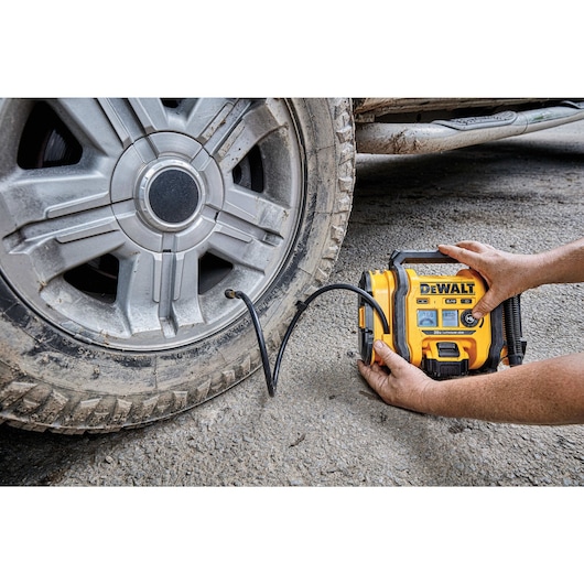 Corded/Cordless Air Inflator being used by a person to inflate a tire