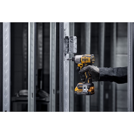 DCF845 20V MAX 1/4 inch 3-Speed Impact Driver with DEWALT POWERSTACK(™) fastening a screw into metal post