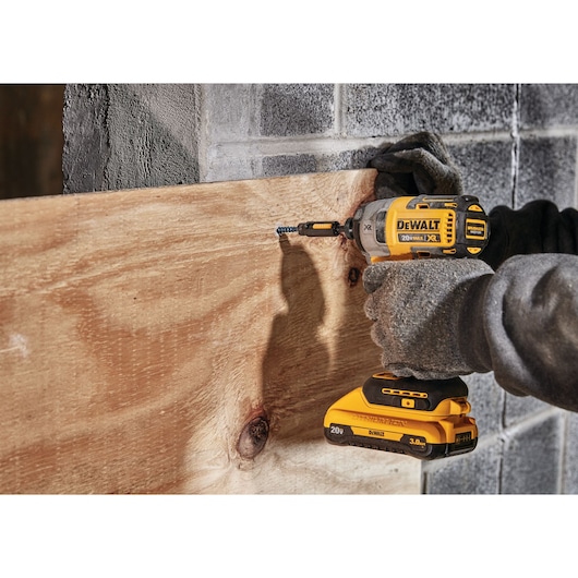 Profile of XR 3-speed impact driver fastening screw through wood on concrete.