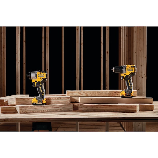 Profile of brushless, cordless drill & impact driver being placed on a work bench