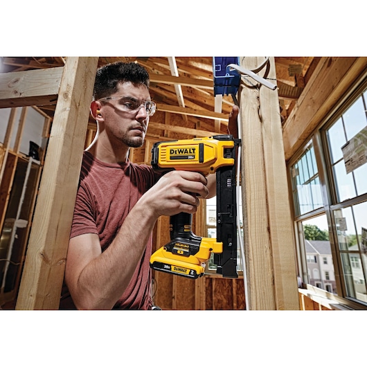 Cordless Cable Stapler in action on a wooden pillar by a construction worker at a construction site