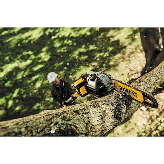 Overhead view of Brushless Cordless Pole Saw being used by a person to cut  branch of tree.