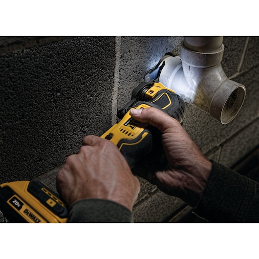 ATOMIC Brushless Cordless Oscillating Multi Tool being used by person to cut through a plumbing pipe