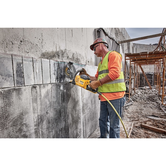 Profile of brushless cordless cut-off saw being used by person on concrete vertically.