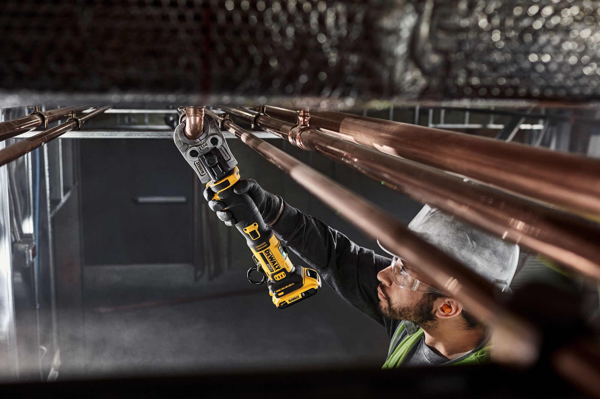 DEWALT Compact Press Tool pressing copper pipe overhead in a mechanical room.