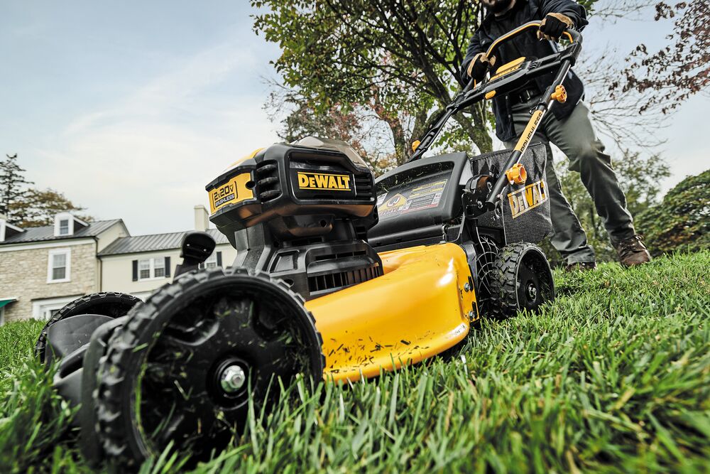 brushless cordless push mower being used by a person to mow a lawn