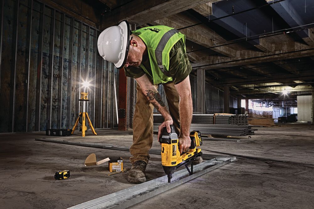 Magazine Cordless Concrete Nailer with a battery being used by a person to install drywall track.
