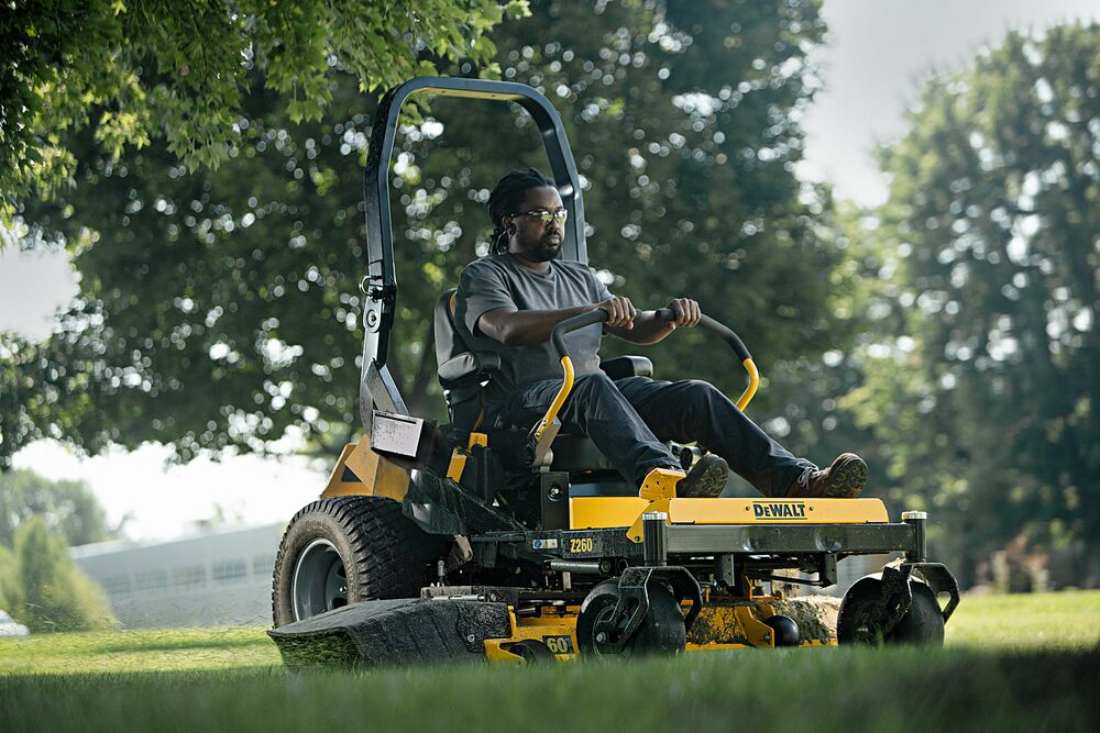 60 inch Kawasaki Gas Hydrostatic Commercial Zero Turn Mower being used by person to mow lawn outdoors.