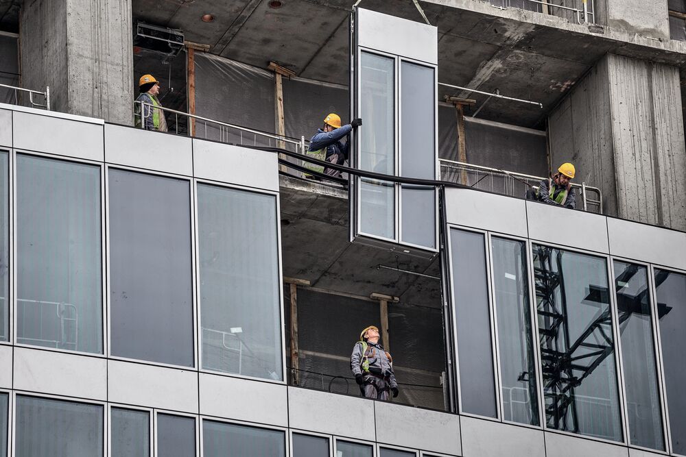 A construction crew lowering a window in place while constructing a building