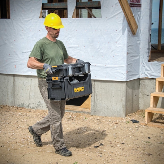tough system tote with a small case attached to it being carried by a worker at a worksite.