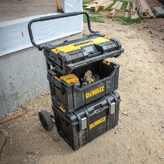 tough system Radio and Charger attached to a carrier with two other cases at a worksite.