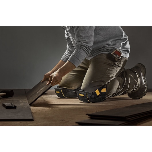 CONSTRUCTION PRO WEARING DEWALT FLOORING KNEE PADS WITH GEL WHILE