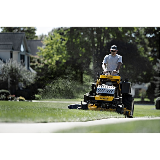 54 inch Kawasaki E F I Gas Hydrostatic Commercial Stand on Zero Turn Mower being used by person to mow lawn.