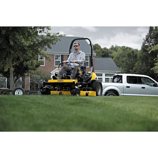 54 inch Kawasaki Gas Hydrostatic Commercial Zero Turn Mower being used by person to mow lawn outdoors.
